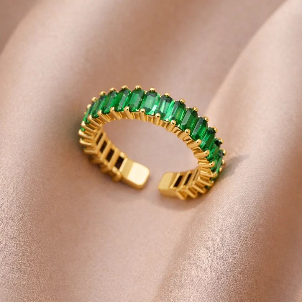 anillo verde dorado Viridia con piedras baguette sobre fondo de seda beige
