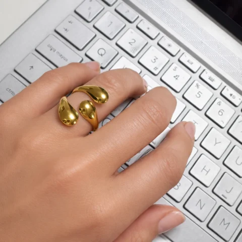 Anillo Bruma ajustable de acero inoxidable dorado puesto en la mano con diseño orgánico elegante.