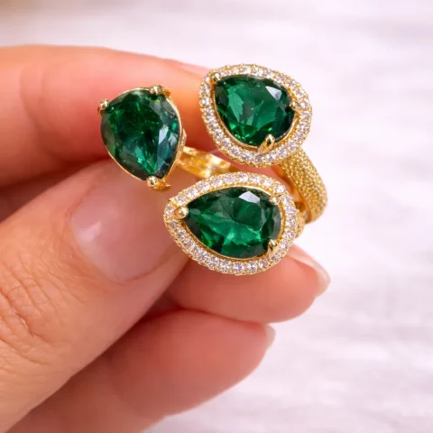anillo Emeria dorado con piedras verdes cogido en mano mujer
