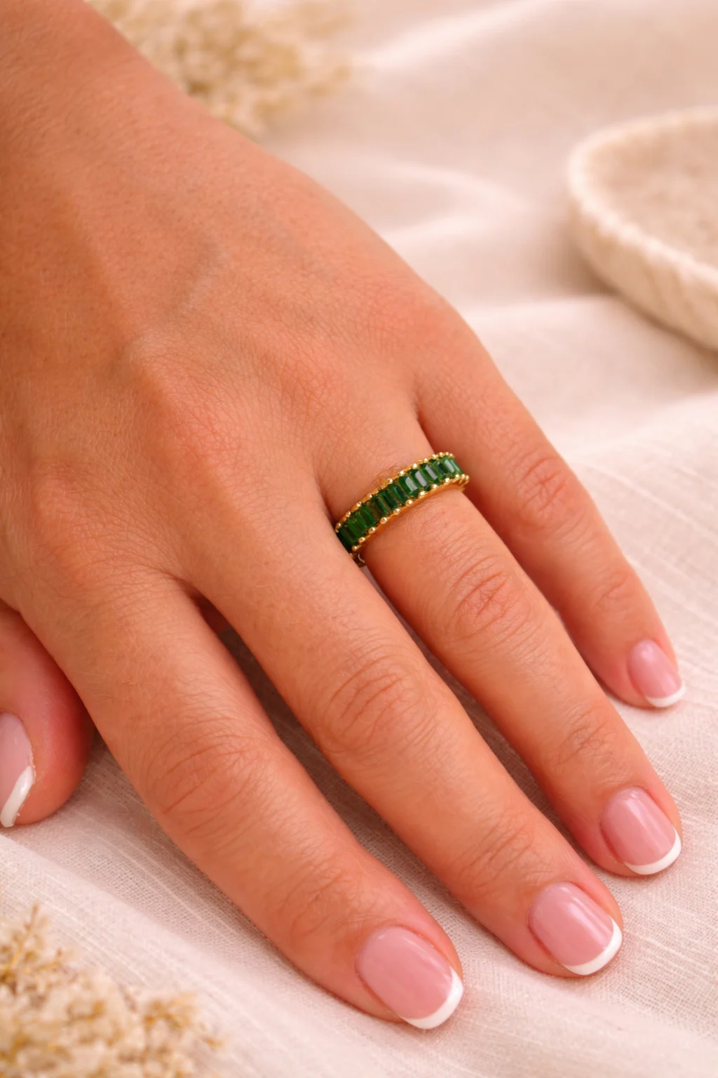 anillo verde dorado Viridia en mano detalle piedras verdes baguette