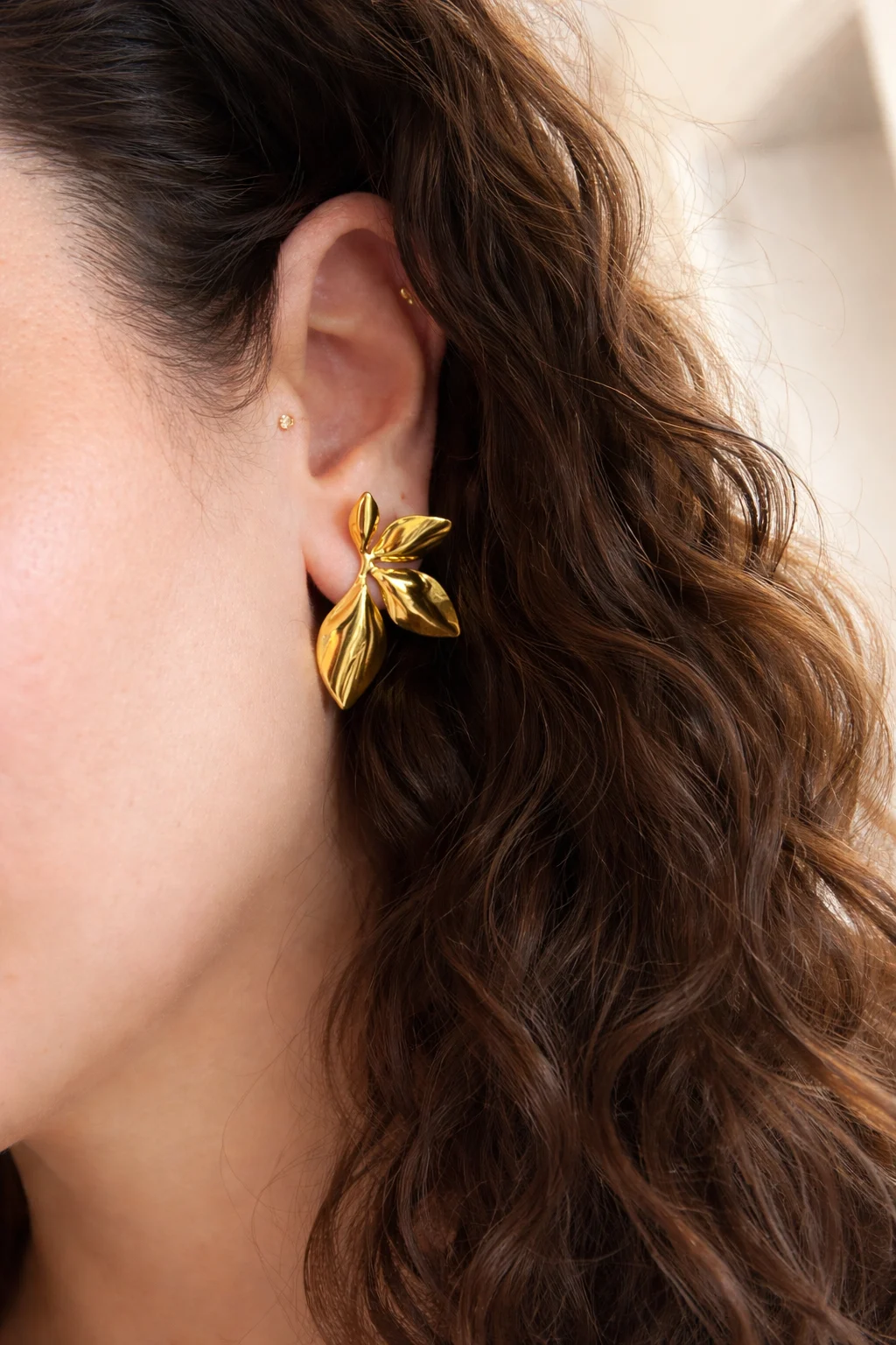 pendientes orquídea dorados puestos en oreja diseño floral elegante